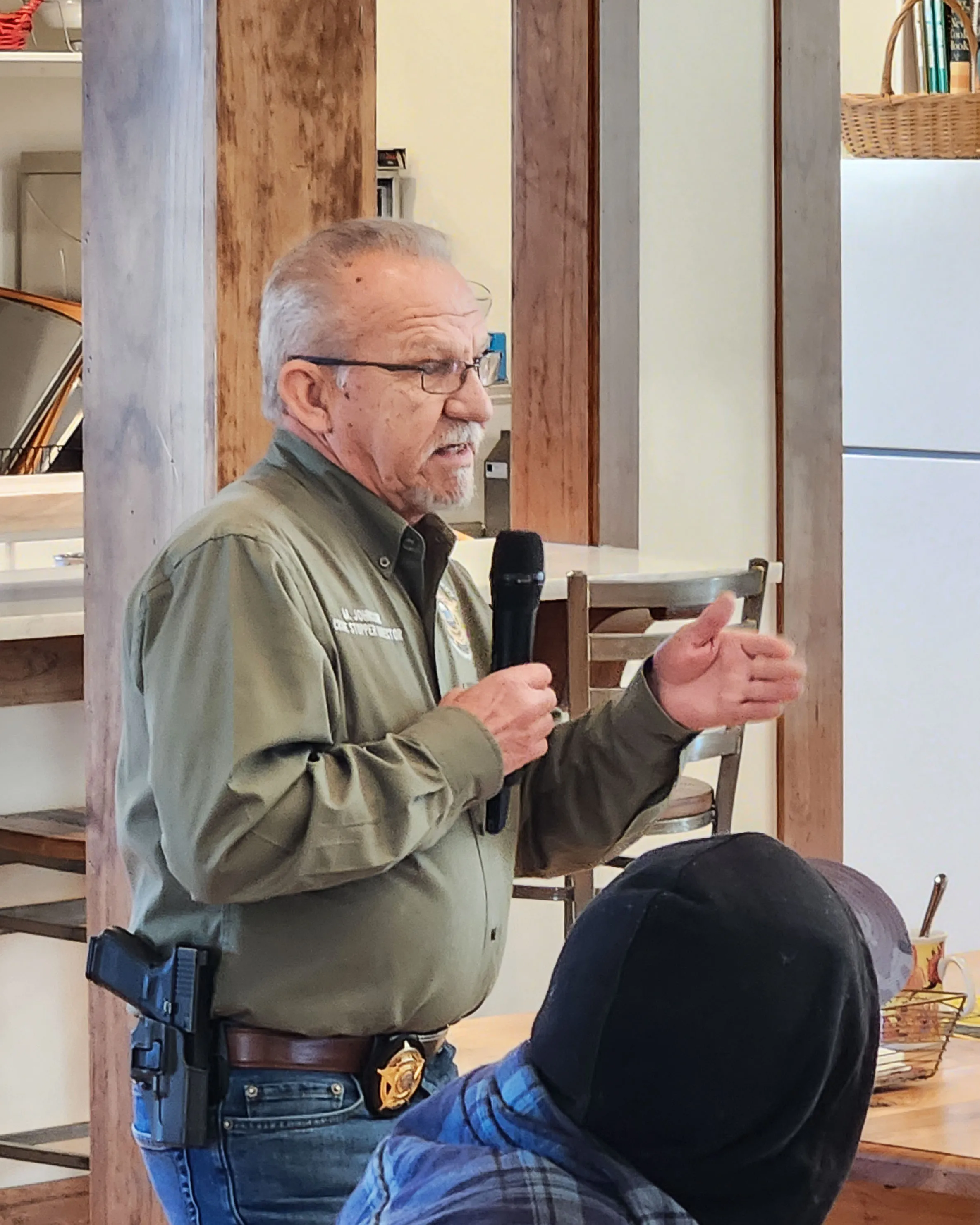 The Crime Stoppers speaker, holding a microphone, explains how to spot scams.