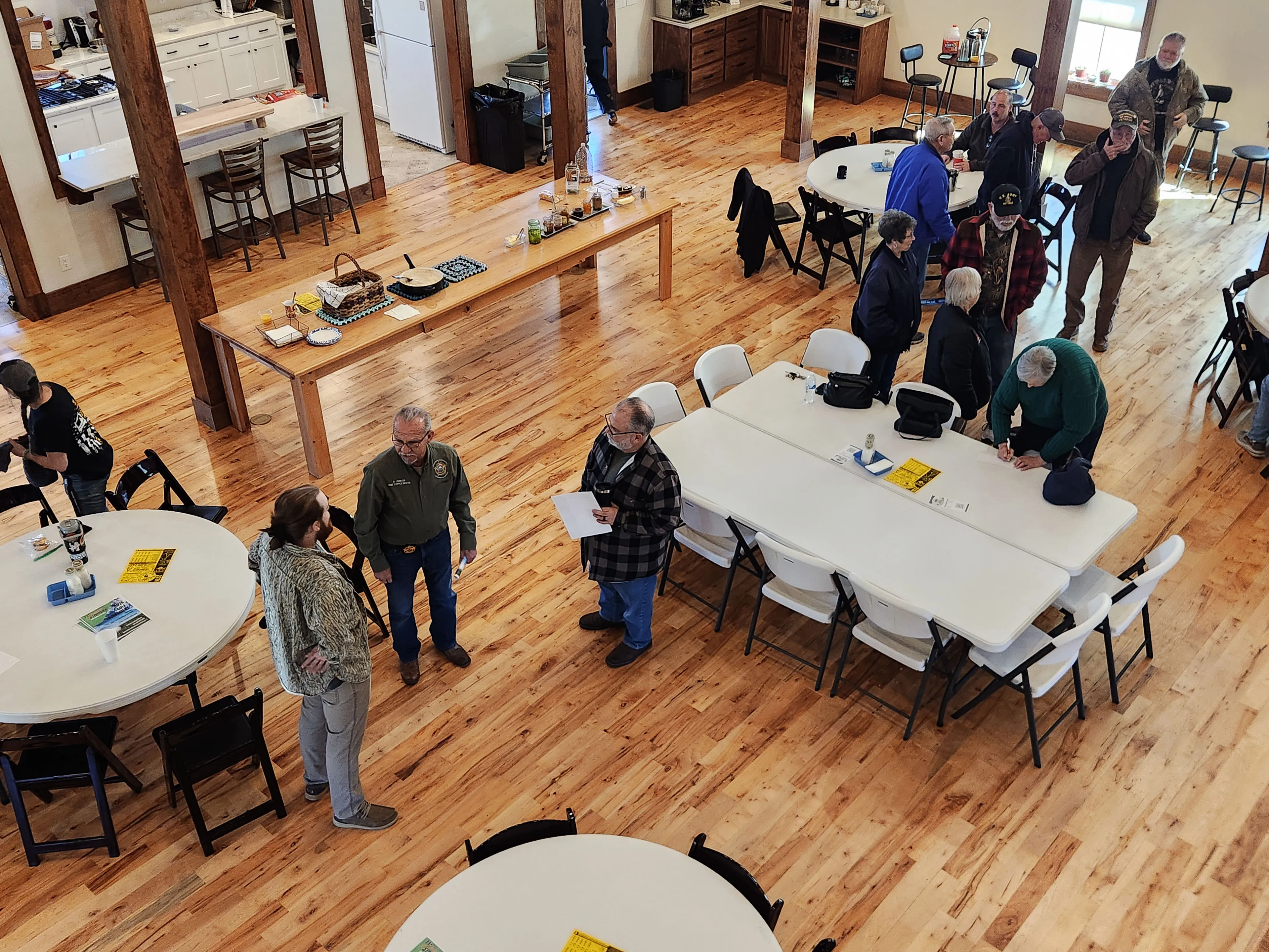 Neighbors stand and chat around long tables in the hall after the presentation.