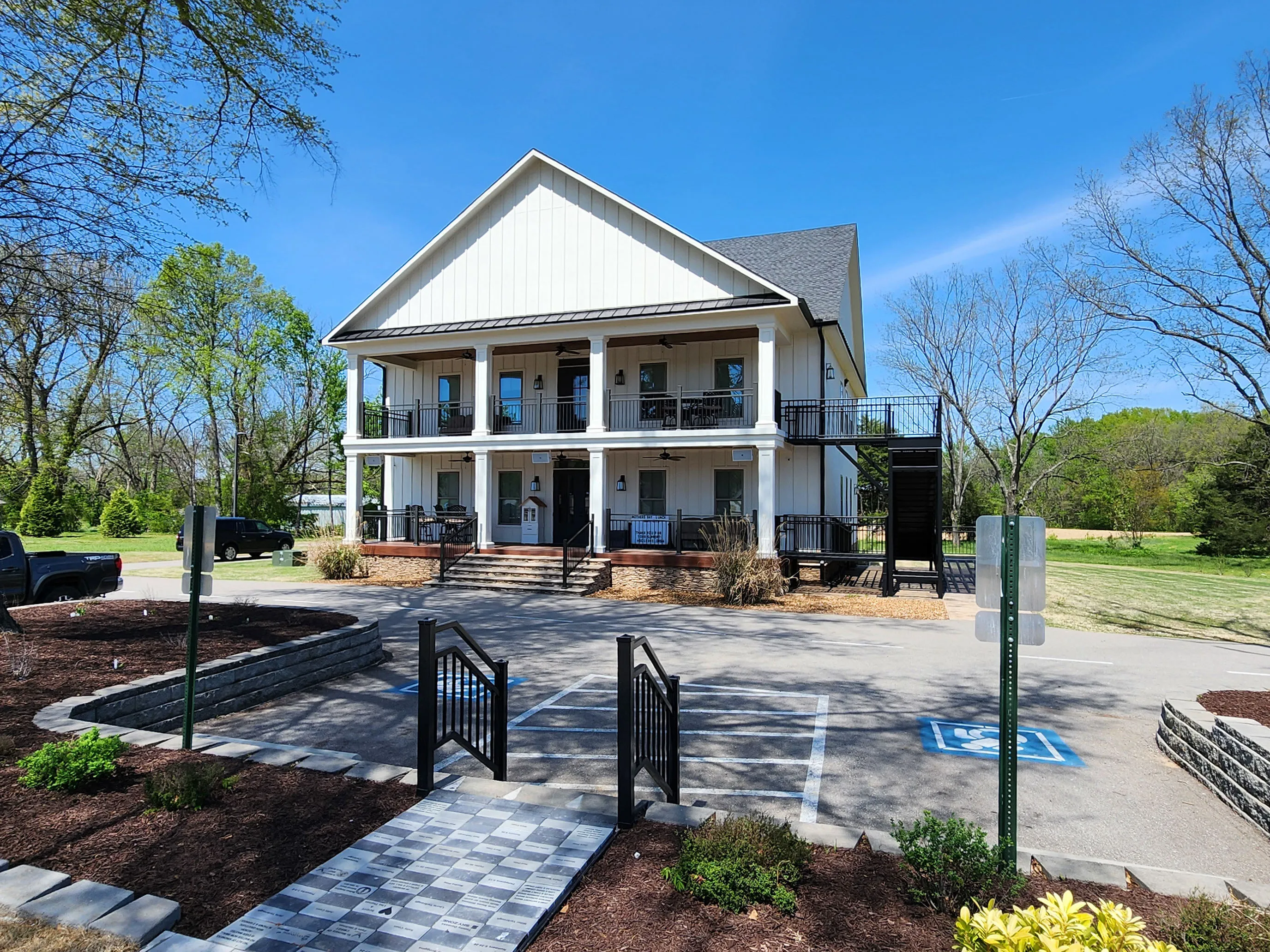 The Ledge’s two-story white building with porches, seen from the front walkway on a sunny day.