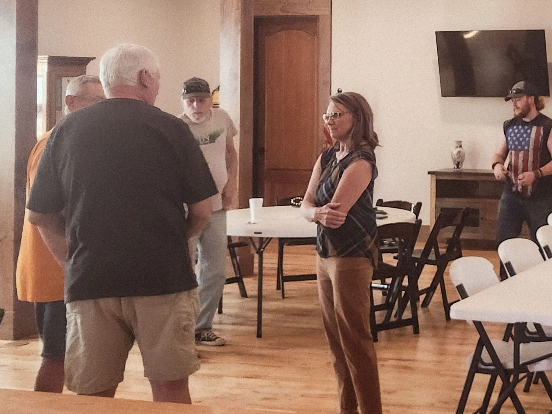 Kim Powell stands talking with neighbors in the middle of the hall.