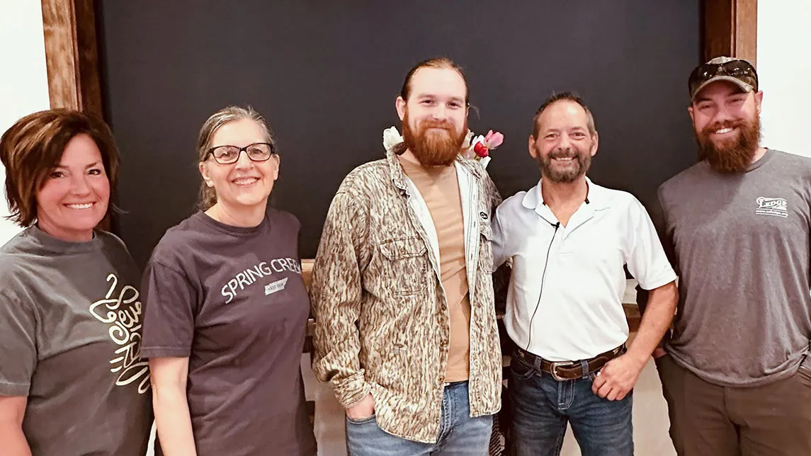 Four guests pose for a photo with the speaker in front of a dark wall.
