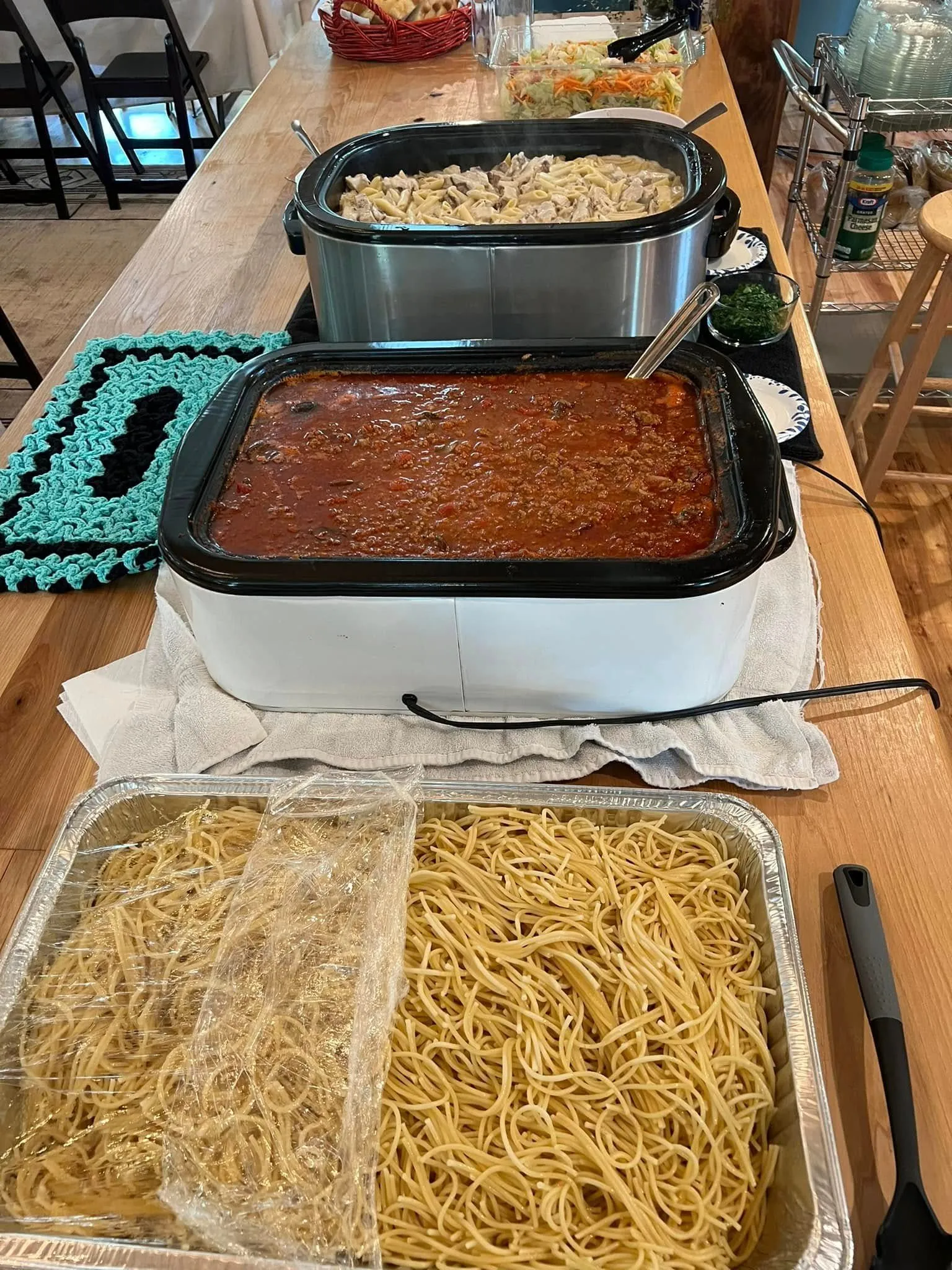 A pan of meatloaf and a tray of pasta on the buffet